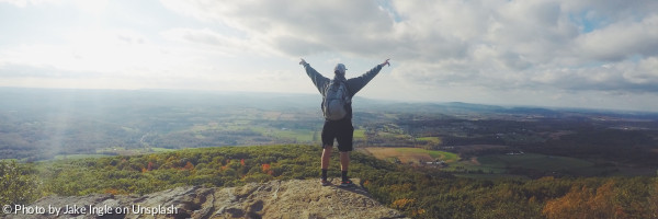 Ein Mann steht auf dem Gipfel eines Berges