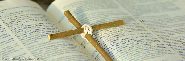 Kreuz aus zusammengebundenen Zweigen auf einer aufgeschlagenen Bibel